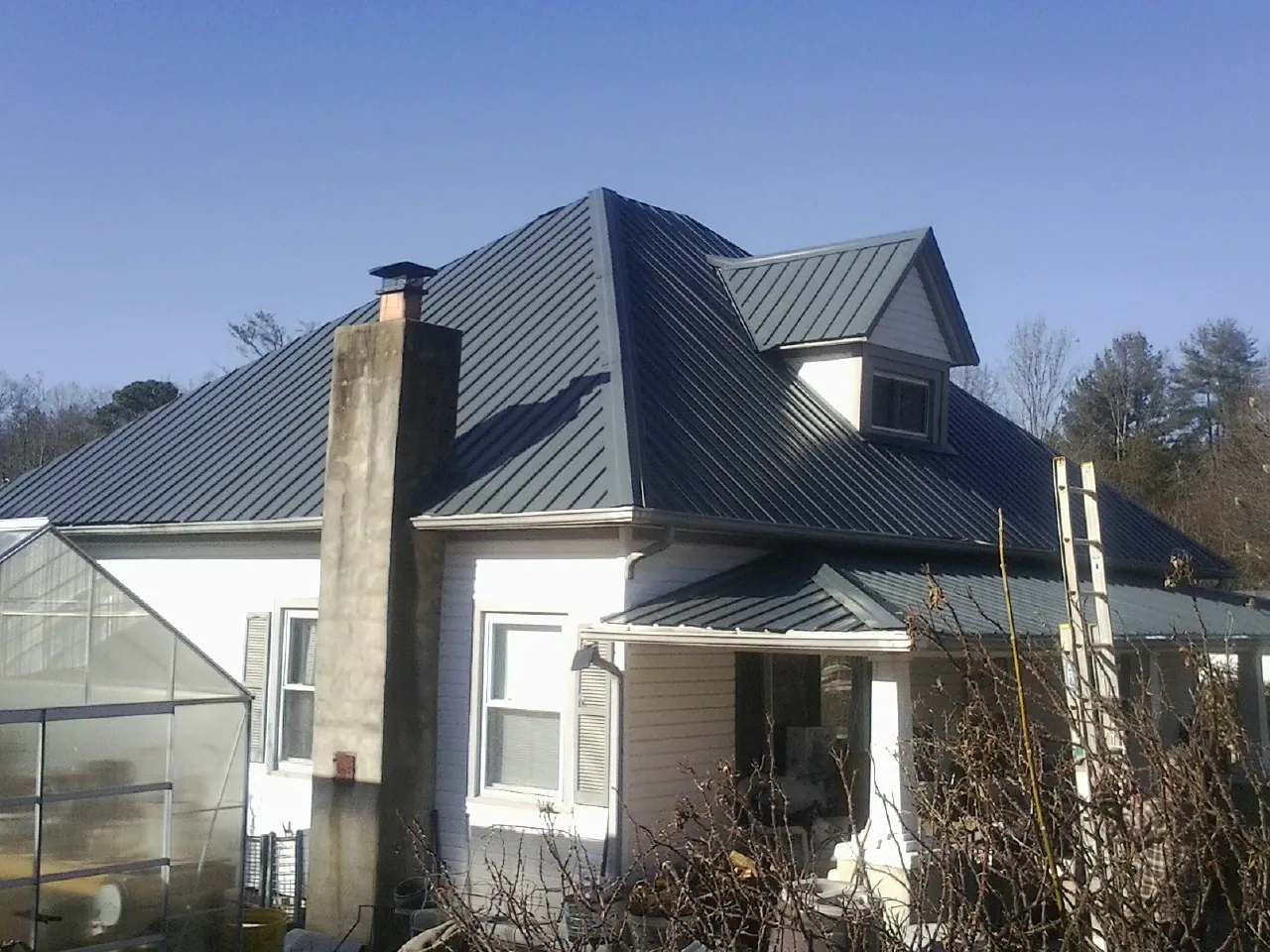 Dark blue standing seam metal roof on a white farmhouse with dormer — Slate & Tile Roof Repair by Roofing Brothers in Verdugo City