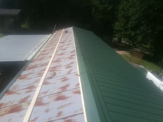 Old rusted panels beside newly installed green metal roofing — Wind Damage Roof Repair by Roofing Brothers in Verdugo City