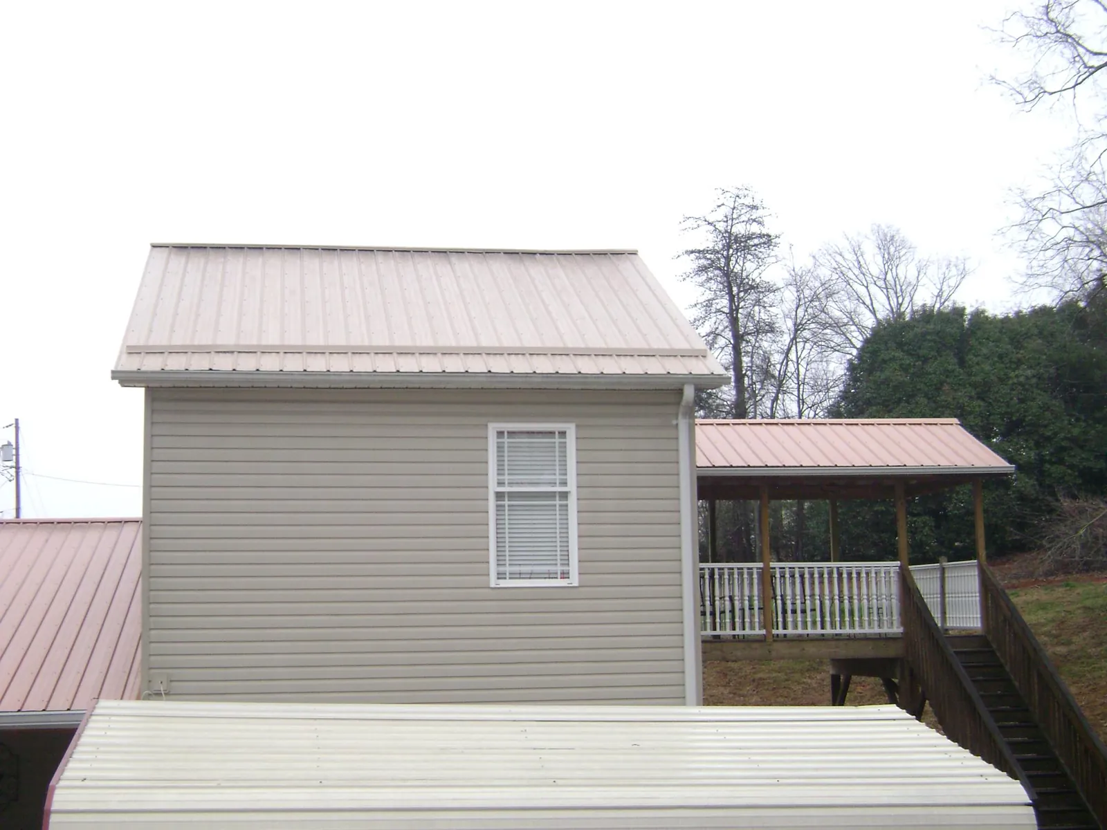 Tan metal roofs on a two story addition and attached porch, from a Roof Replacement job in Verdugo City