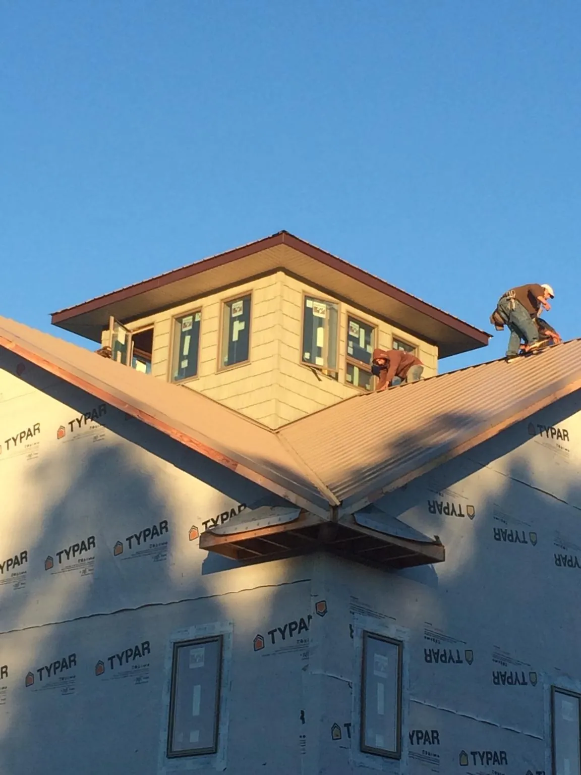 Roofers working around a rooftop cupola on a new metal roof at sunset — Roof Waterproofing in Verdugo City by Roofing Brothers